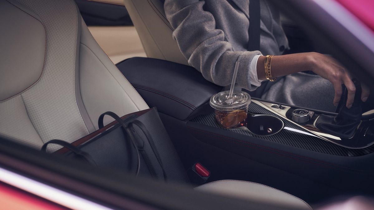 Interior View Of Woman Sitting In The Driver Seat Of Her 2020 INFINITI Q60 Coupe Highlighting Leather Seats and Cupholders
